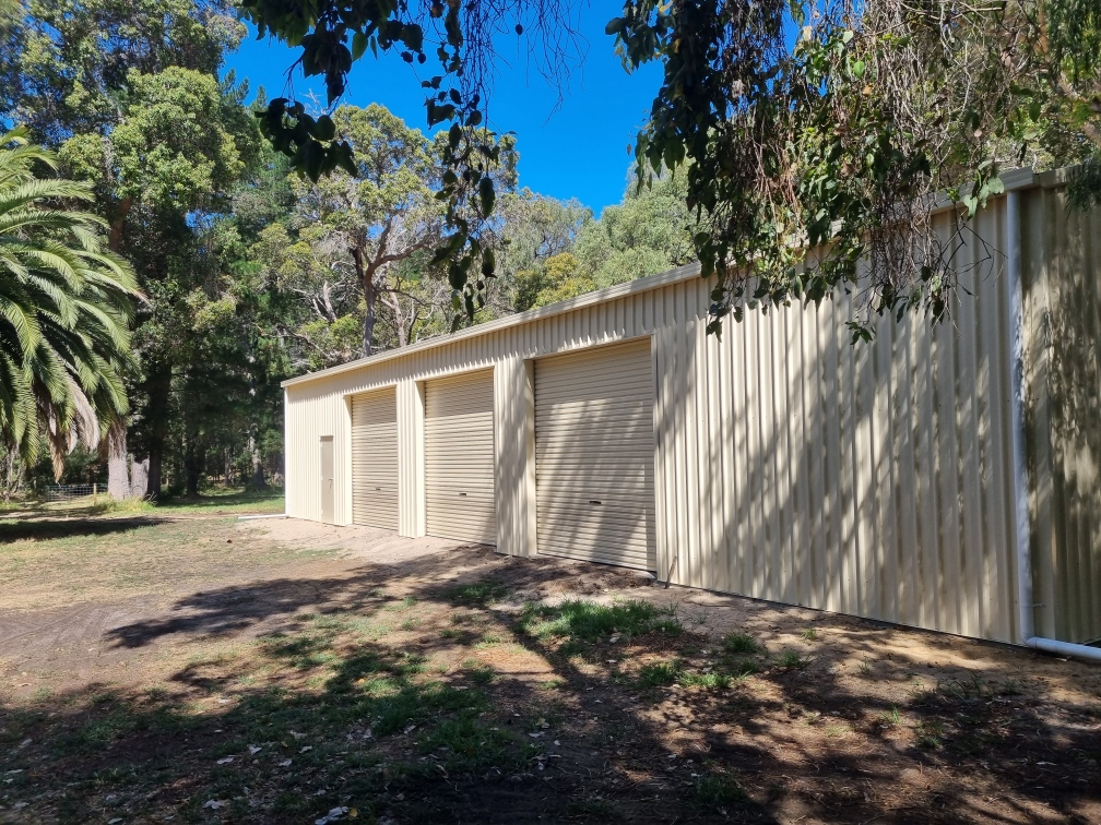 Large beige shed in lush forest setting.