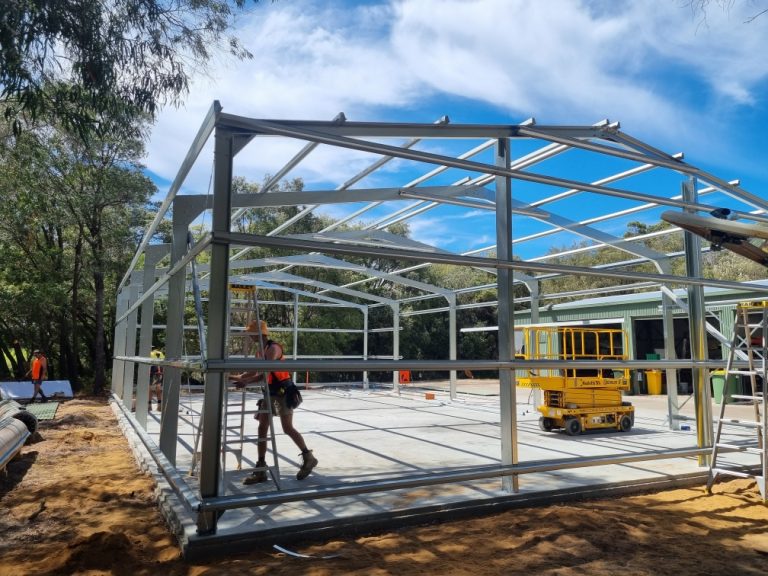 Construction workers assembling shed steel structure frame.